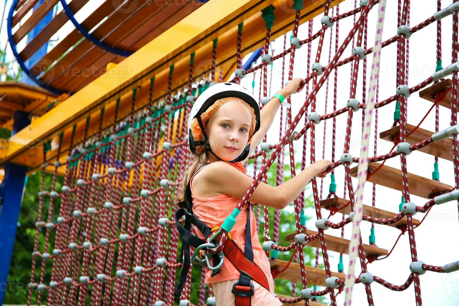 Happy girl on rope way in amusement center for children. photo