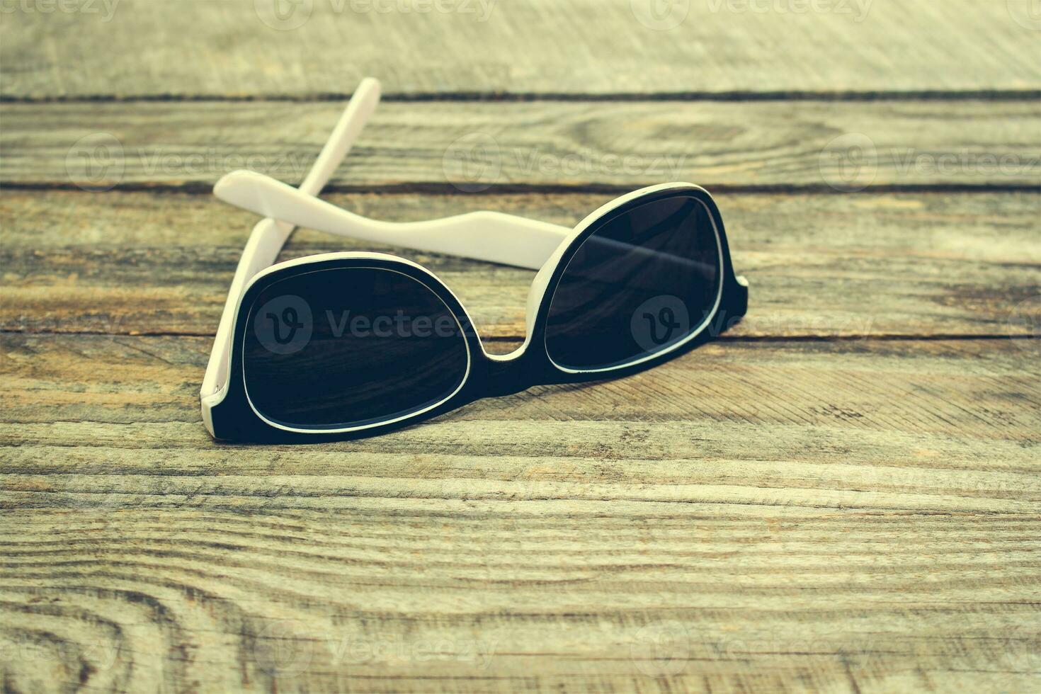 Sunglasses on wooden background. Toned image. photo