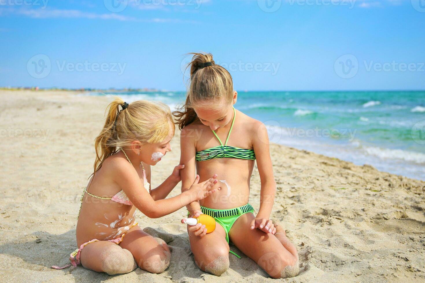 hermana aplicando protector protector solar en joven niño. niña sorteos Dom crema en su estómago. foto