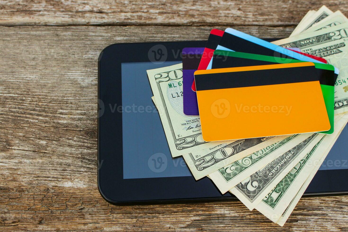 Credit card, dollars, computer tablet on wooden background. Top view. photo