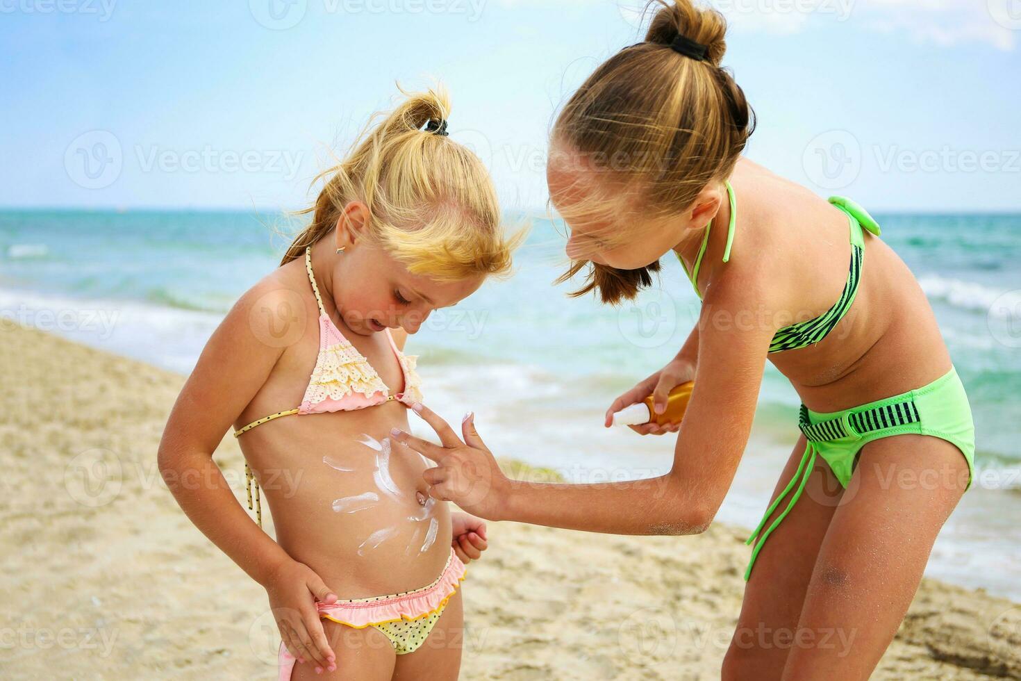 Sister applying protective sunscreen on young child. photo