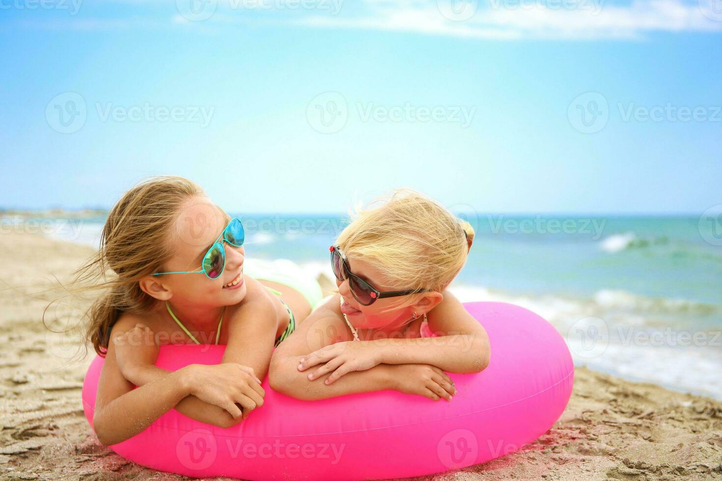 Happy girls lying on pink inflatable circle. photo