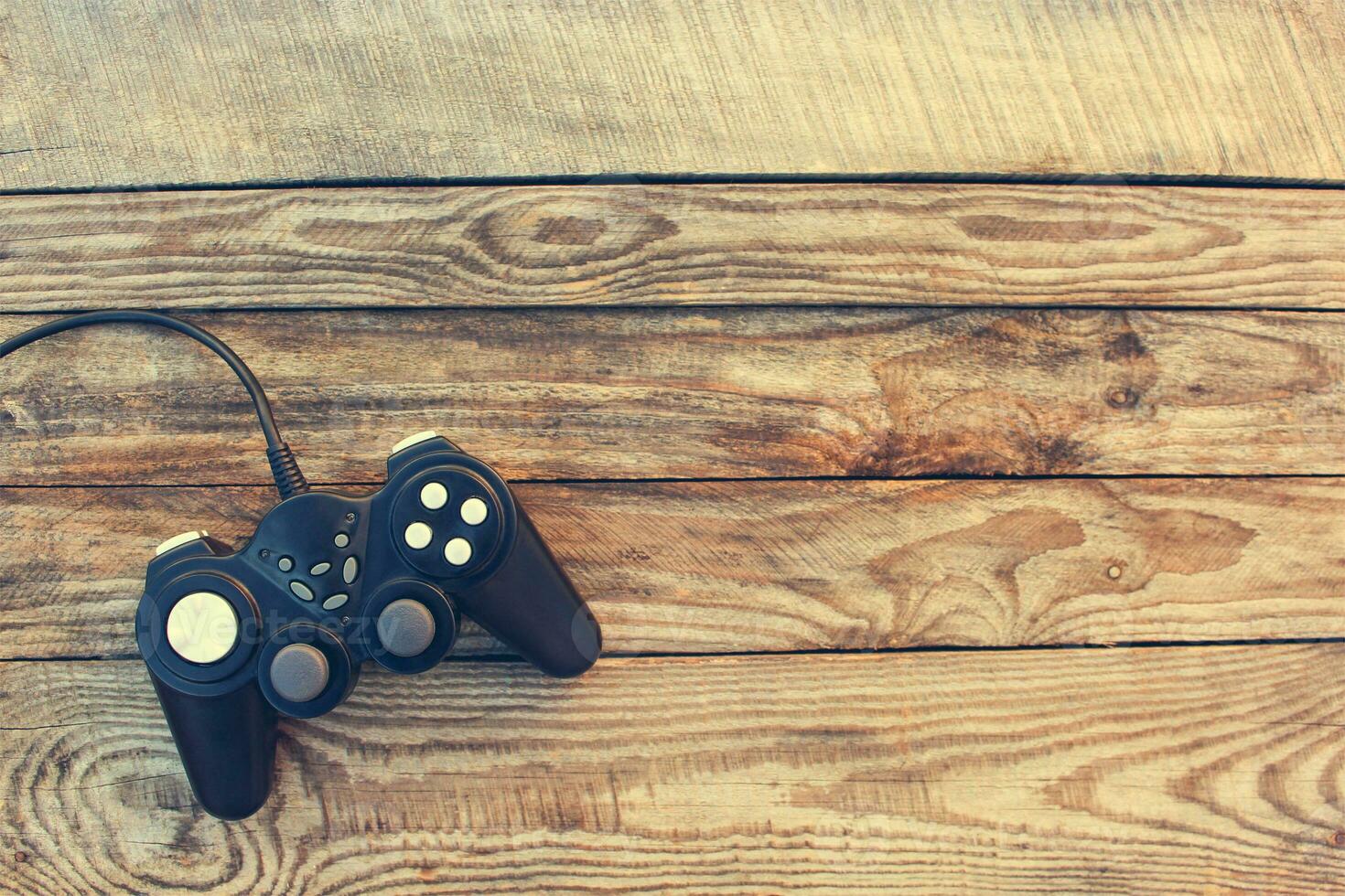 Video game controller on old wooden background. Toned image. Top view. photo