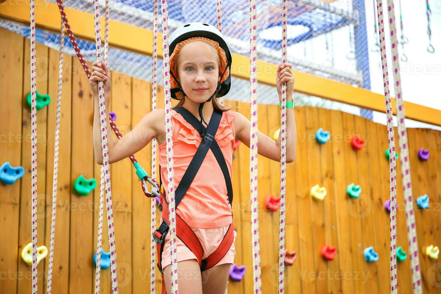 Happy girl on rope way in amusement center for children. photo