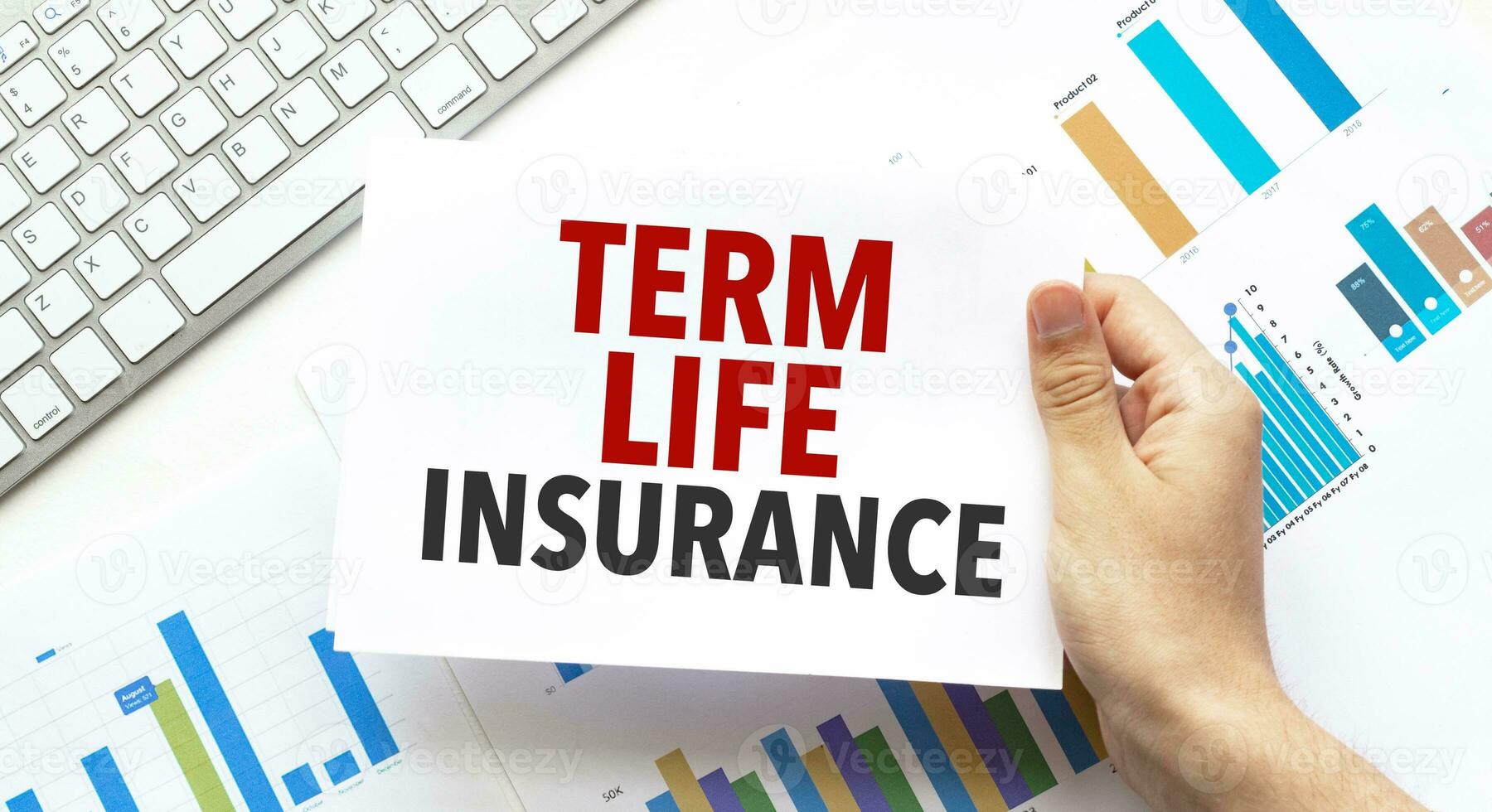 Businessman holding a card with text TERM LIFE INSURANCE .Keyboard, diagram and white background photo