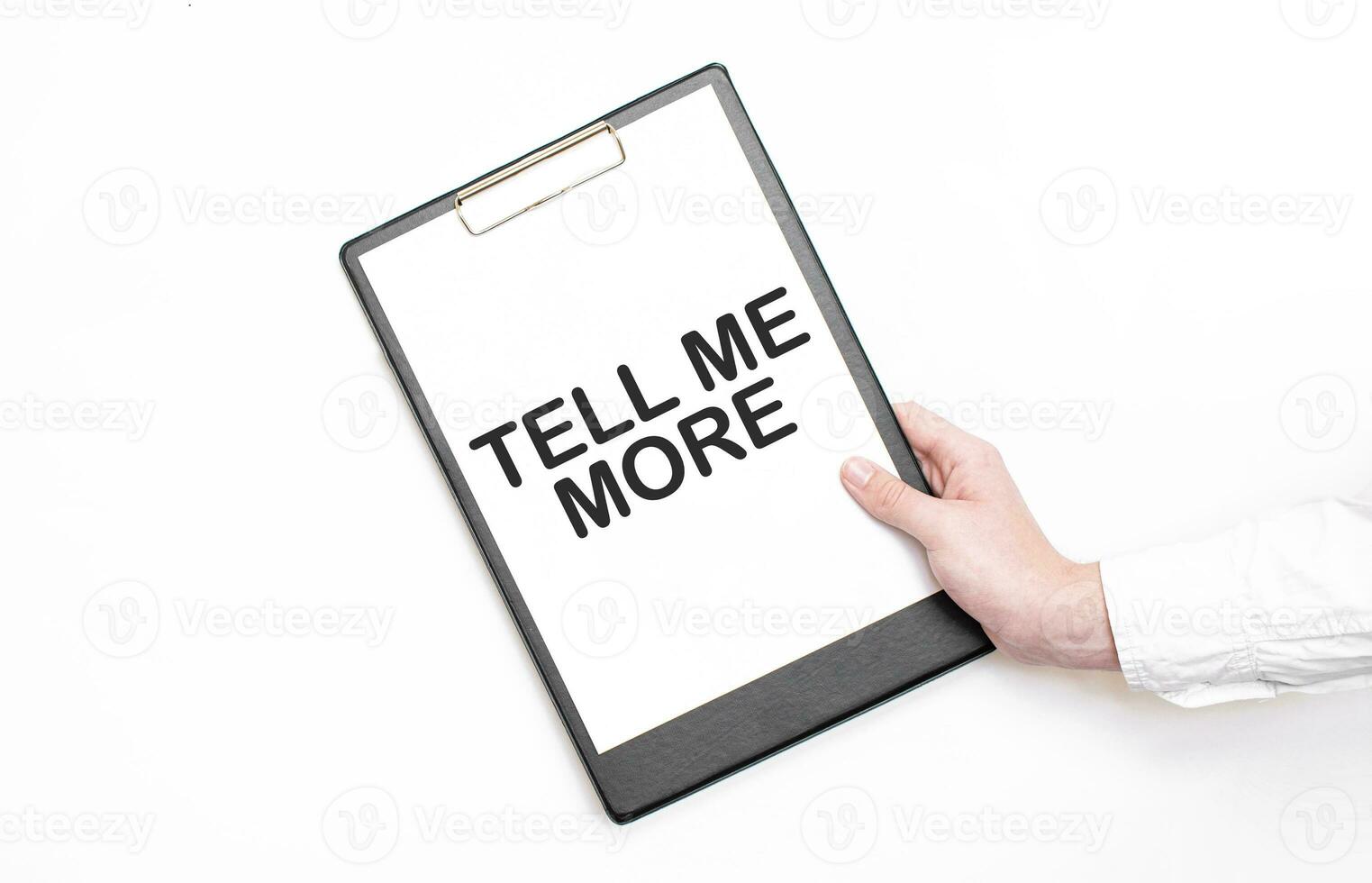 A businessman holds a folder with paper sheet with the text TELL ME MORE. Business concept. photo