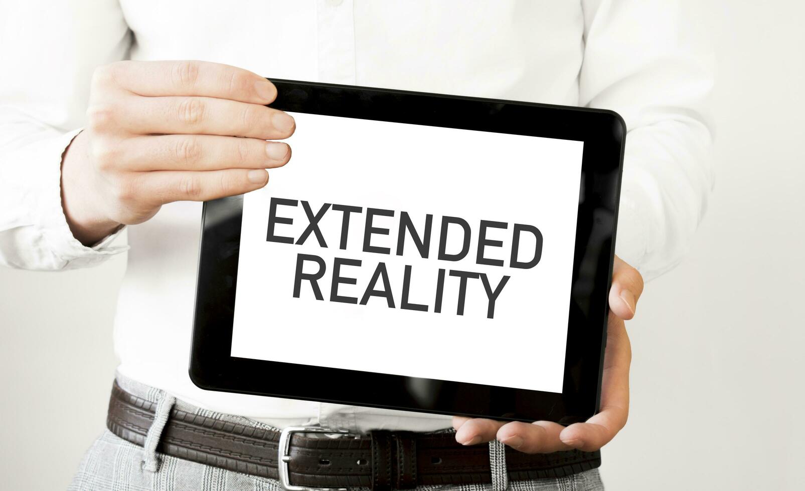 Text EXTENDED REALITY on tablet display in businessman hands on the white background. Business concept photo