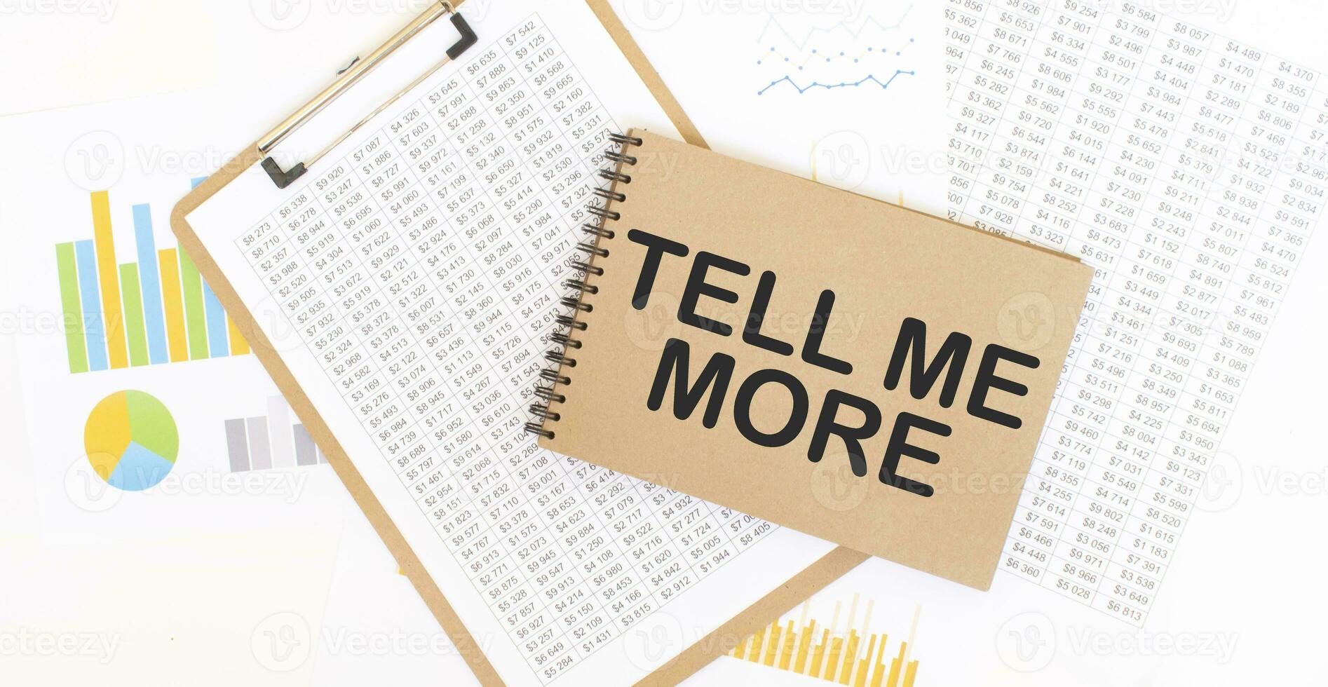 Text TELL ME MORE on brown paper notepad on the table with diagram. Business concept photo