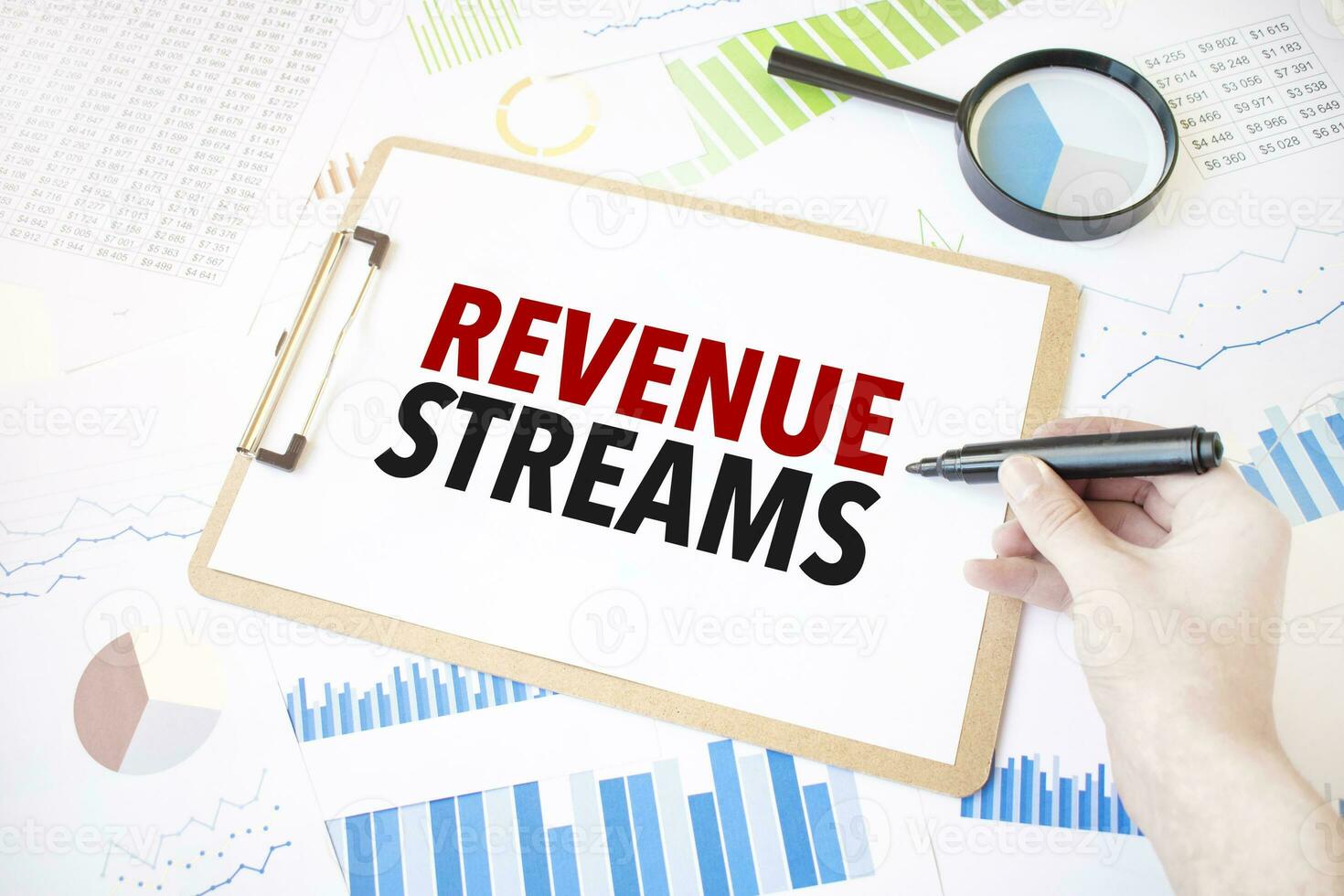 Text REVENUE STREAMS on white paper sheet and marker on businessman hand on the diagram. Business concept photo