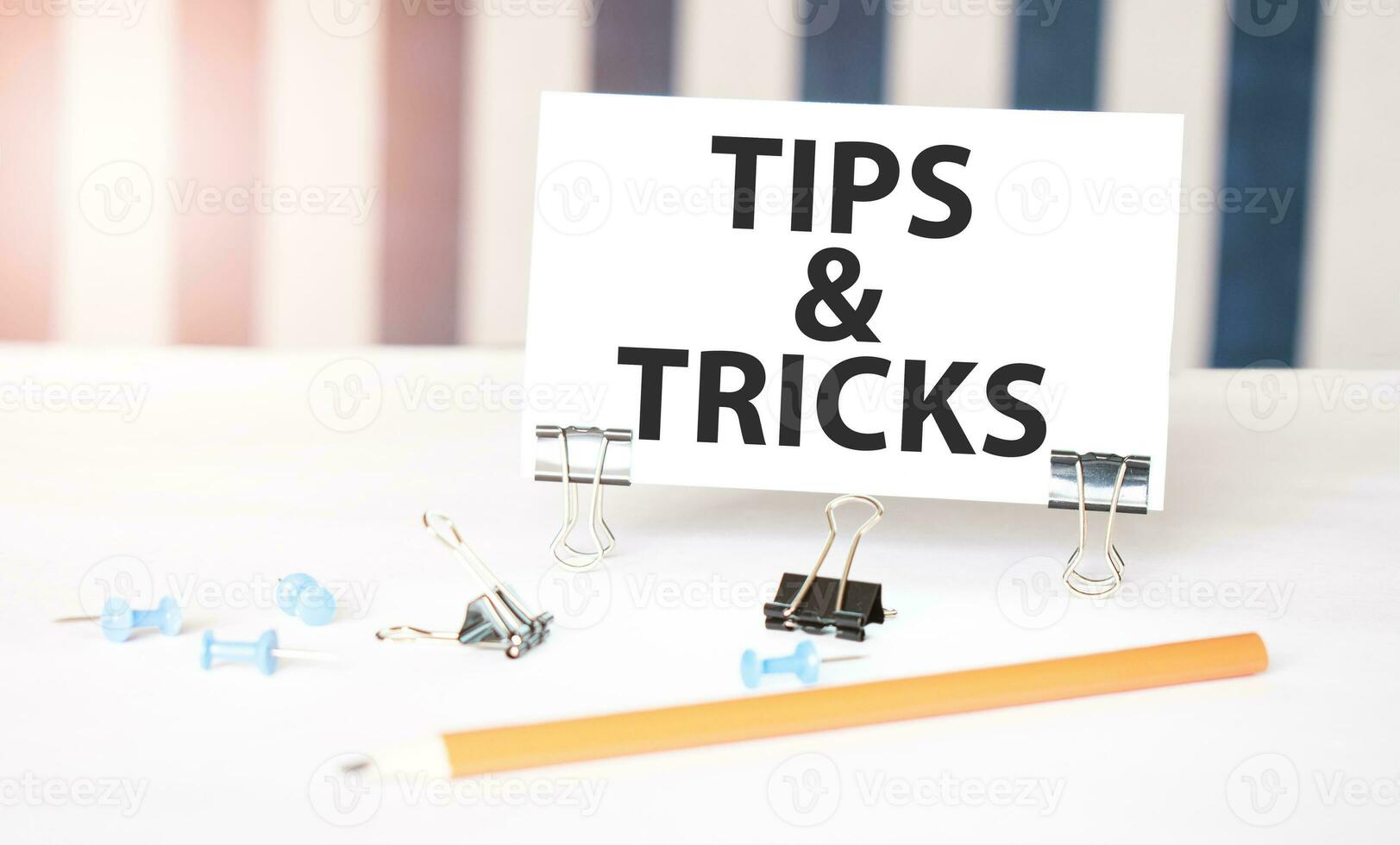 TIPS AND TRICKS sign on paper on white desk with office tools. Blue and white background photo