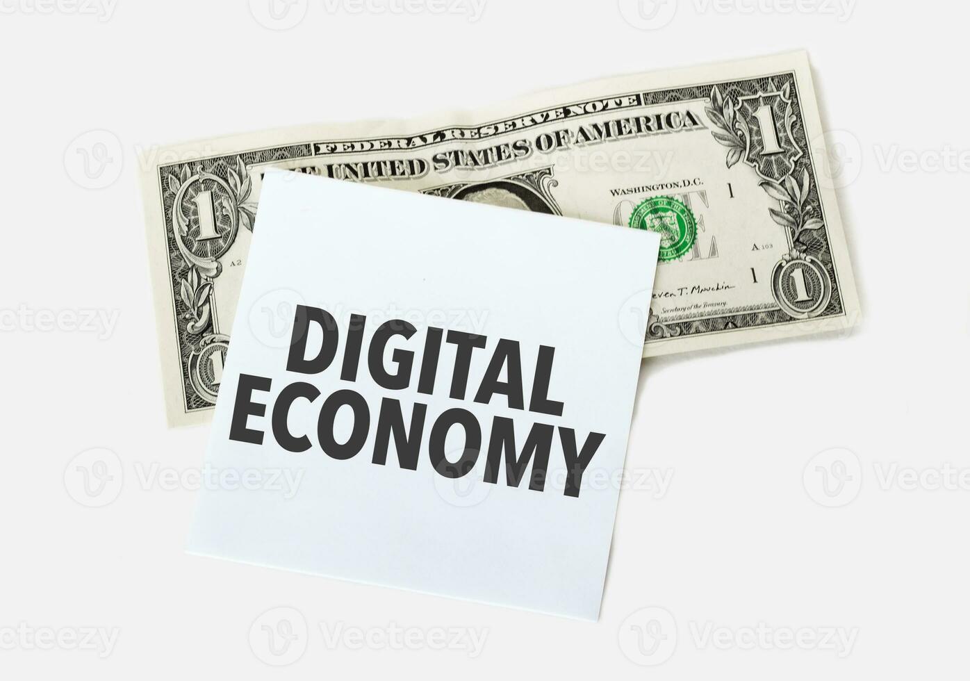 1 dollar bill and white notepad sheet on the white background. Text DIGITAL ECONOMY photo