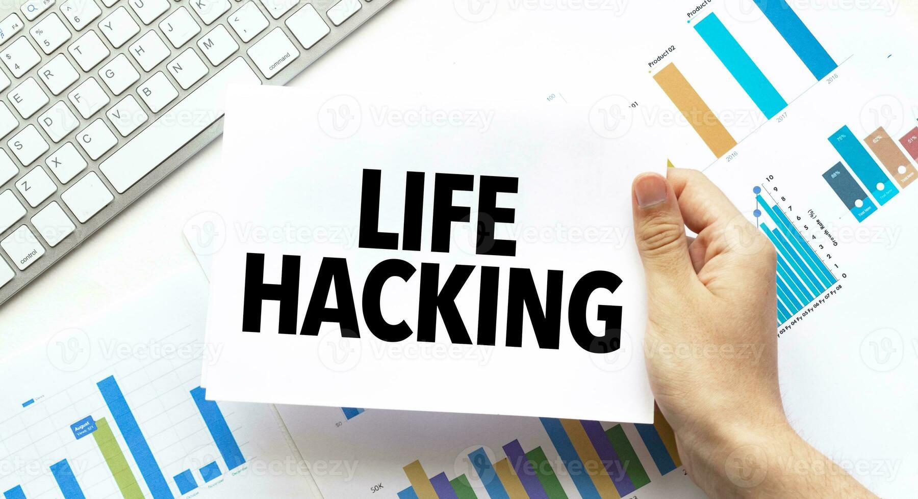 Businessman holding a card with text LIFE HACKING .Keyboard, diagram and white background photo