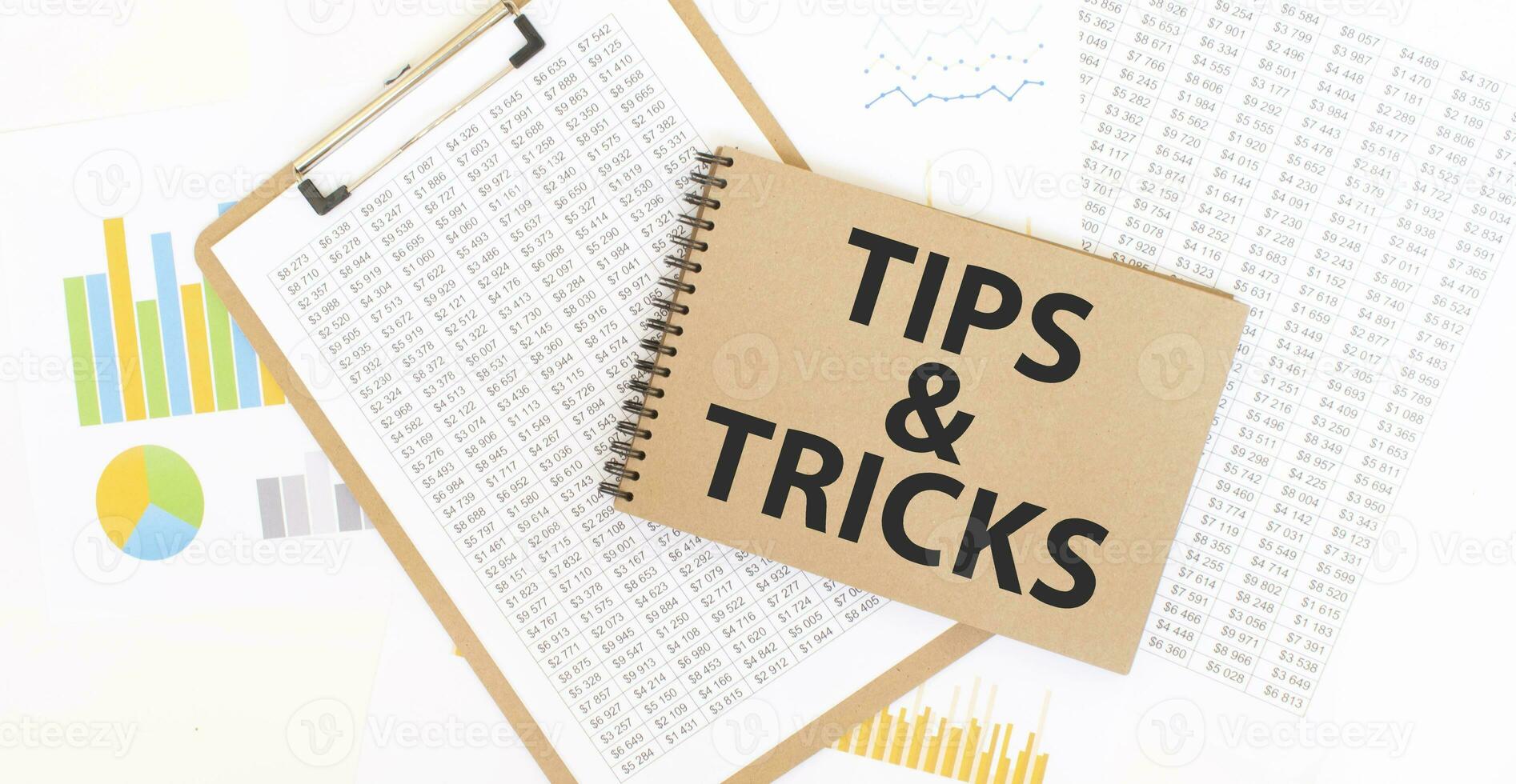 Text TIPS AND TRICKS on brown paper notepad on the table with diagram. Business concept photo