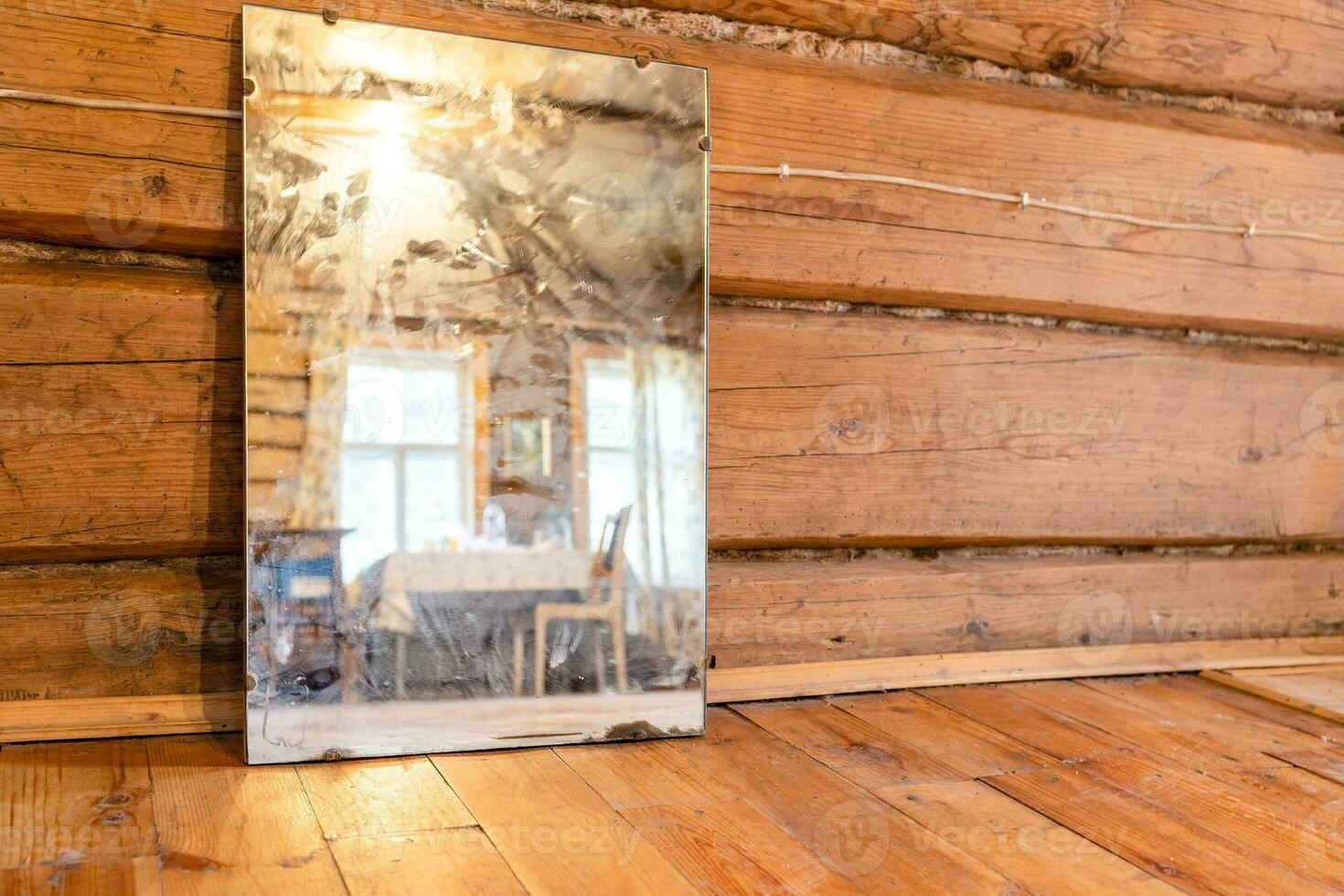 old mirror stands on wooden floor in log house photo