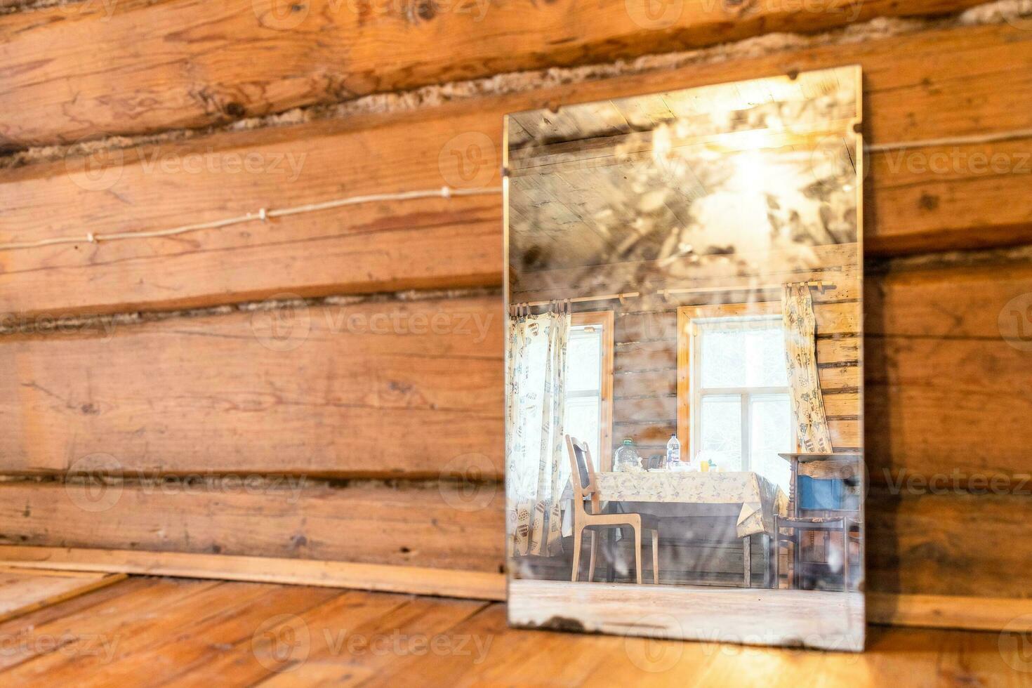 table is reflected in old mirror standing on floor photo