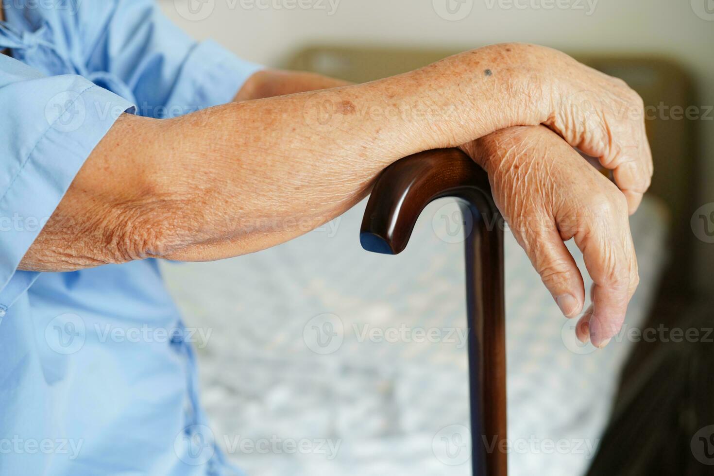 Asian elderly disability woman patient holding walking stick in wrinkled hand at hospital. photo