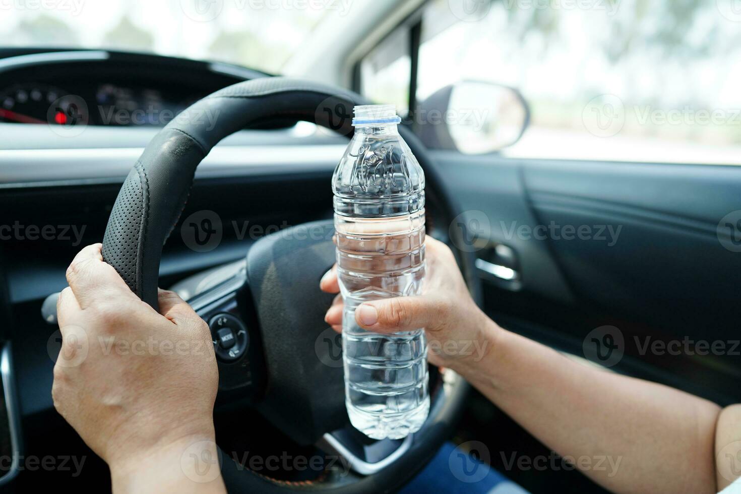 asiático mujer conductor sostener bebida en auto, peligroso y riesgo un accidente. foto