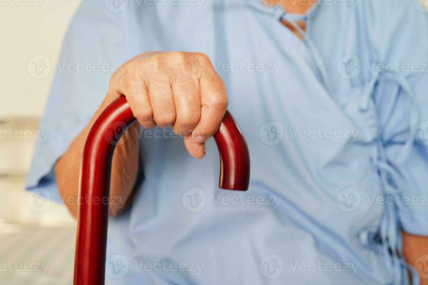 Asian elderly disability woman patient holding walking stick in wrinkled hand at hospital. photo