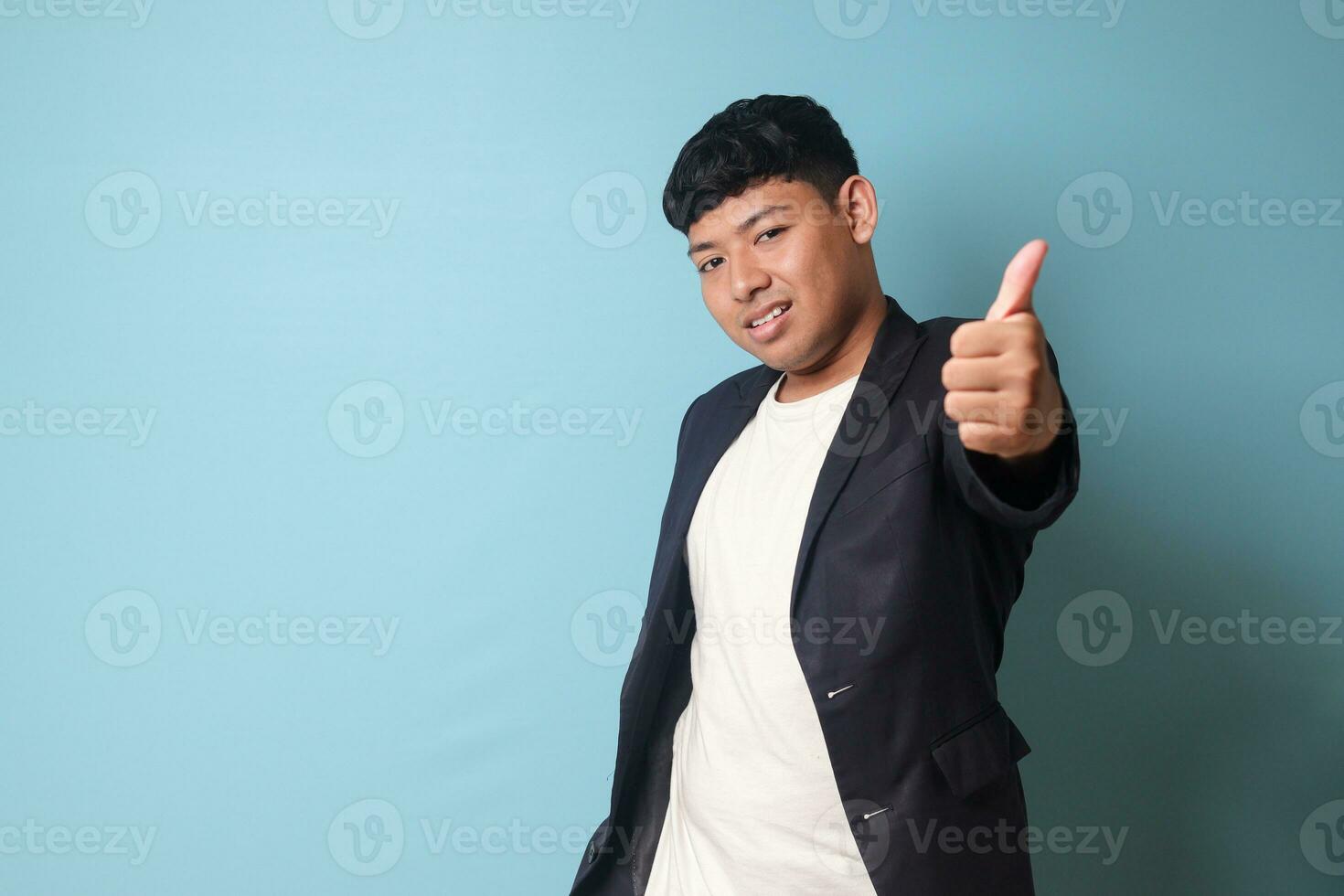 Portrait of young Asian business man in casual suit with happy expressions with thumb up gesture. Isolated image on blue background photo