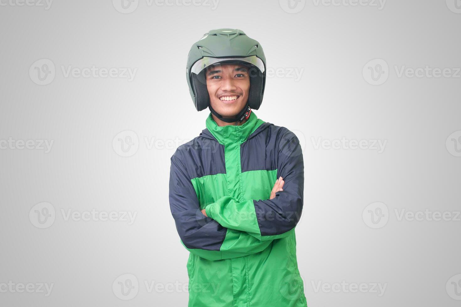 Portrait of Asian online taxi driver wearing green jacket and helmet, standing with crossed arms. Isolated image on white background photo