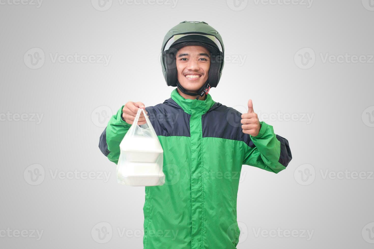 Portrait of Asian online taxi driver wearing green jacket and helmet holding food wrapped in foam plastic box. Isolated image on white background photo