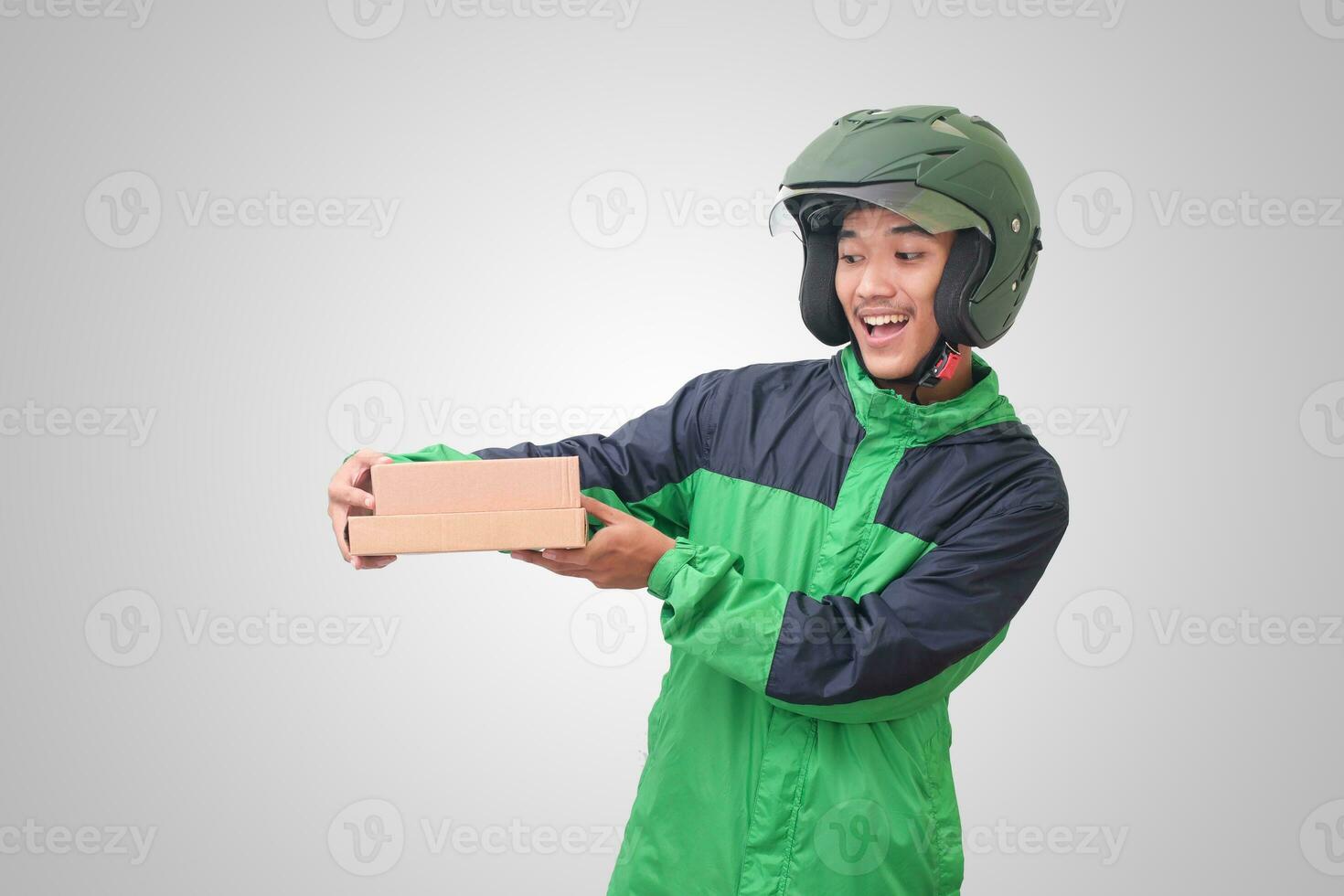 Portrait of Asian online courier driver wearing green jacket and helmet delivering package and box for customer. Isolated image on white background photo