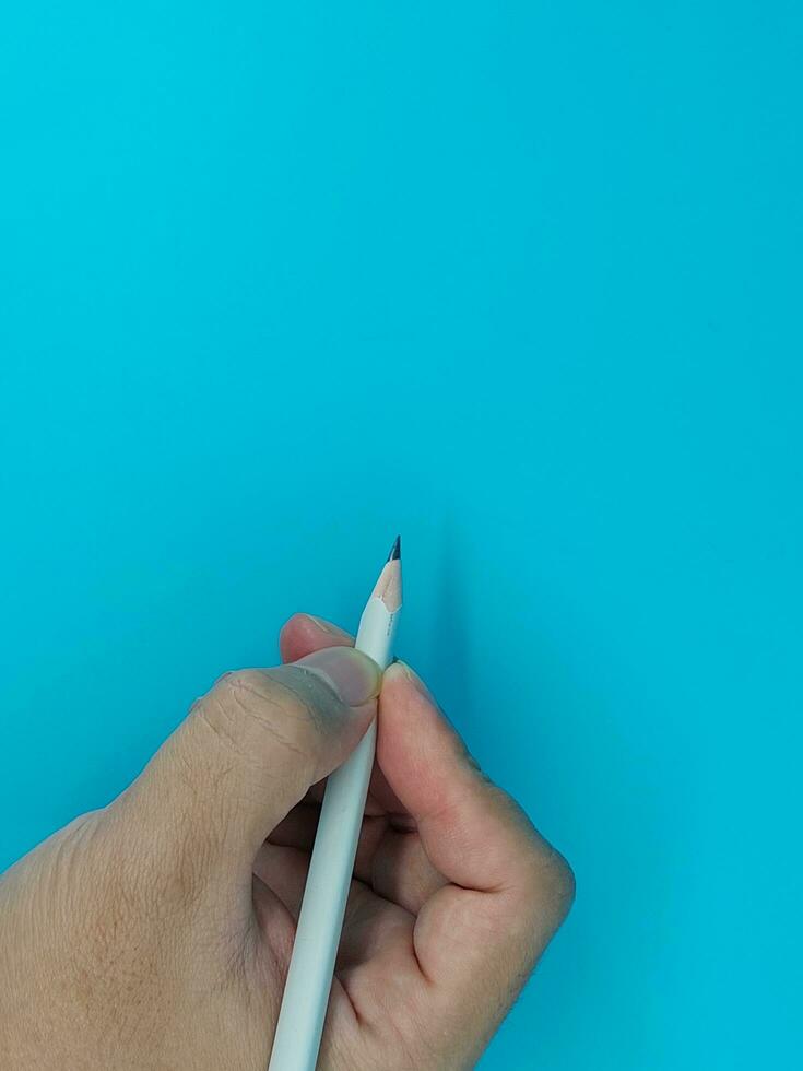 The hand holds an acutely sharpened pencil photo