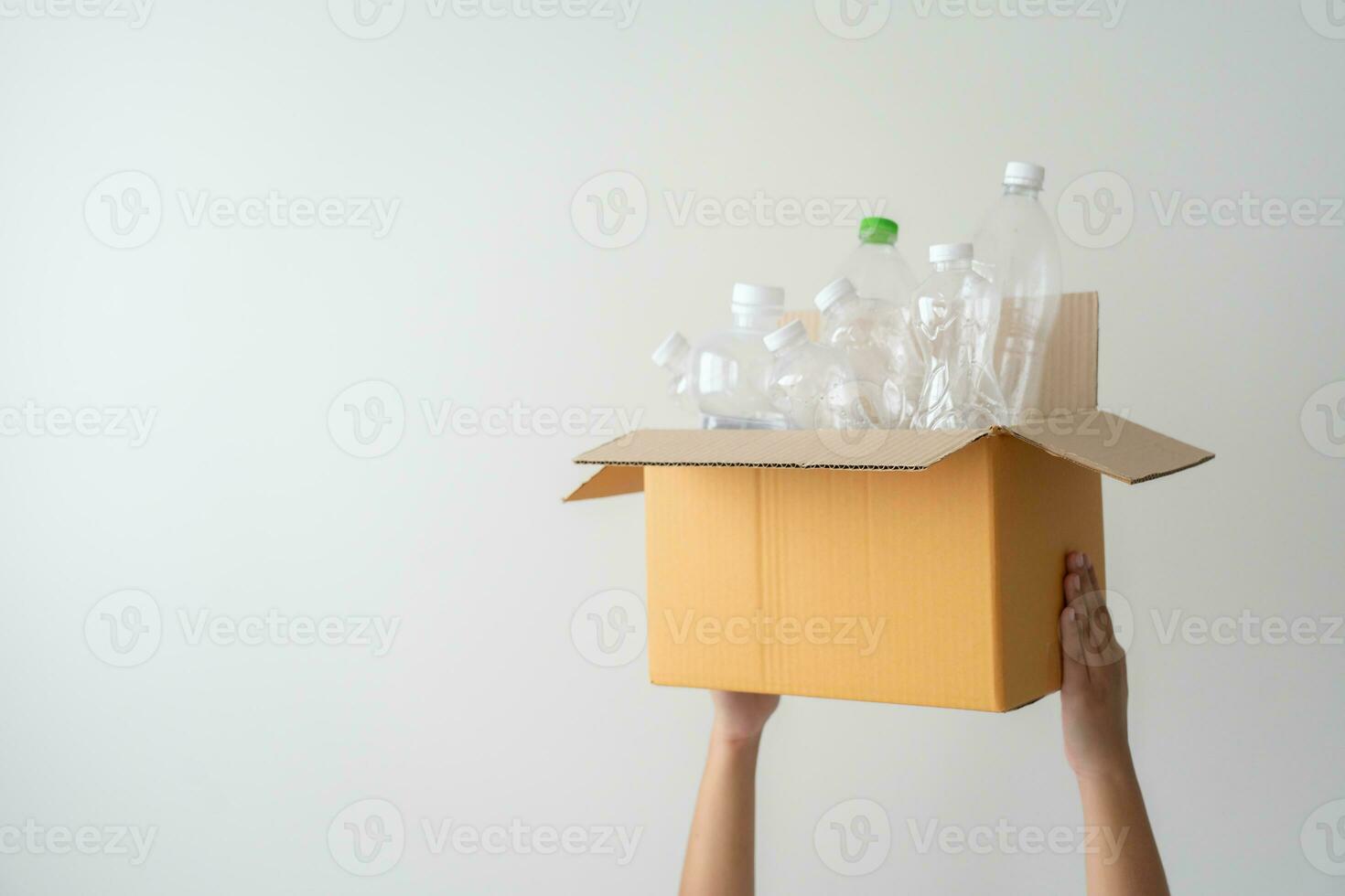 People launch a campaign to recycle used empty plastic bottles. Hands holding cardboard box full with plastic bottle ready to recycle. Concept of reuse, reduce, recycle to save the environment photo