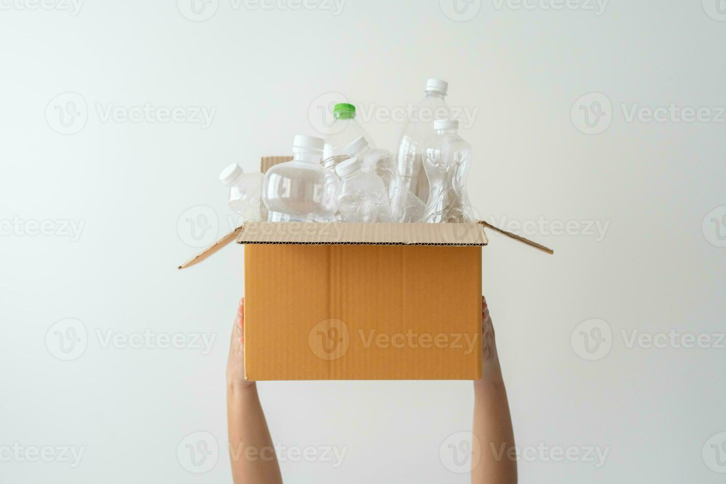 People launch a campaign to recycle used empty plastic bottles. Hands holding cardboard box full with plastic bottle ready to recycle. Concept of reuse, reduce, recycle to save the environment photo