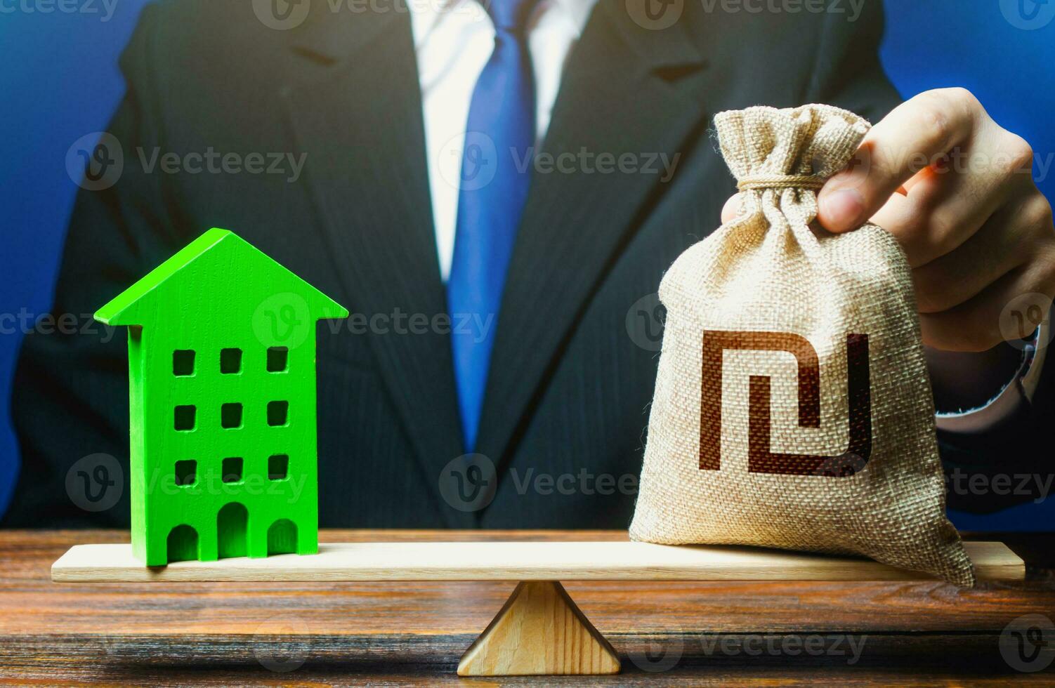 Businessman puts israeli shekel money bag on scales and green house. Profitability housing of eco technologies. Reduced CO2 emissions, energy efficiency. Investment in renovation. Payback period photo