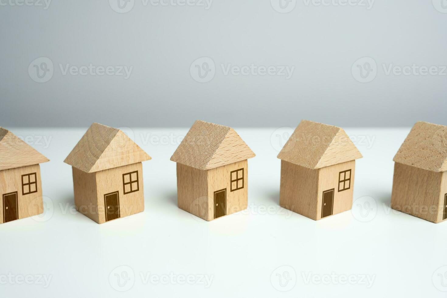 Wooden toy houses stand in a row. Find most suitable housing options. Offers on real estate market. Mortgage. Valuation of residential buildings. Realtor services. Buying and selling. photo