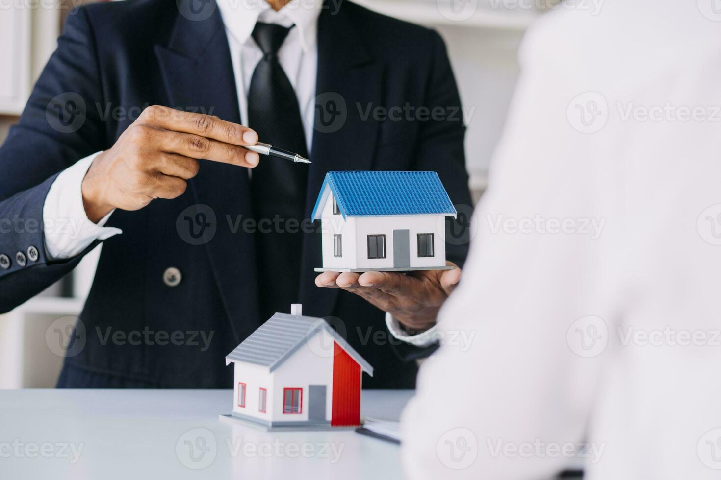 A couple is approaching a housing project to buy, and they are discussing details and advice with a salesperson in a housing project. Real estate trading ideas with couples. photo