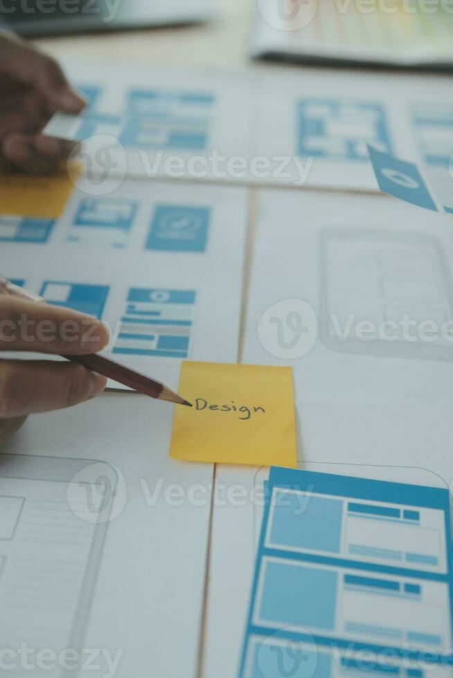 Close up ux developer and ui designer brainstorming about mobile app interface wireframe design on table with customer breif and color code at modern office.Creative digital development agency photo