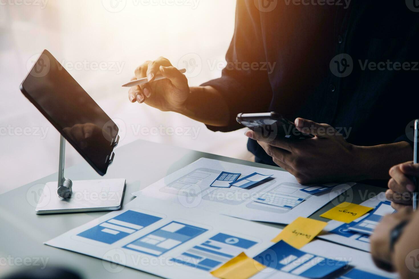 Close up ux developer and ui designer brainstorming about mobile app interface wireframe design on table with customer breif and color code at modern office.Creative digital development agency photo