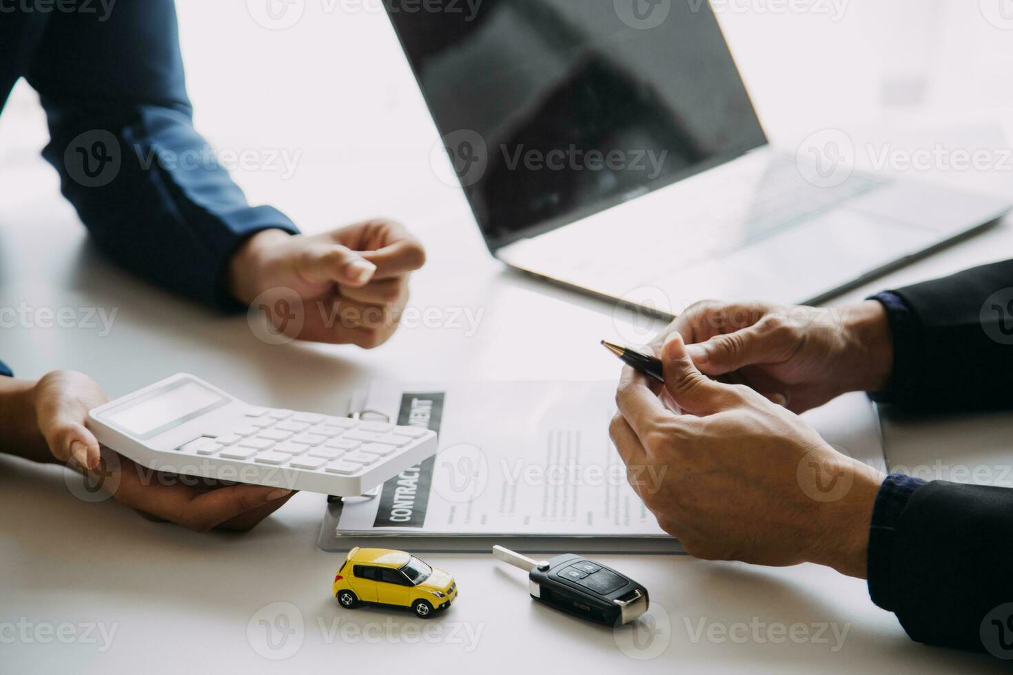 A car rental company employee is handing out the car keys to the renter after discussing the rental details and conditions together with the renter signing a car rental agreement. Concept car rental. photo