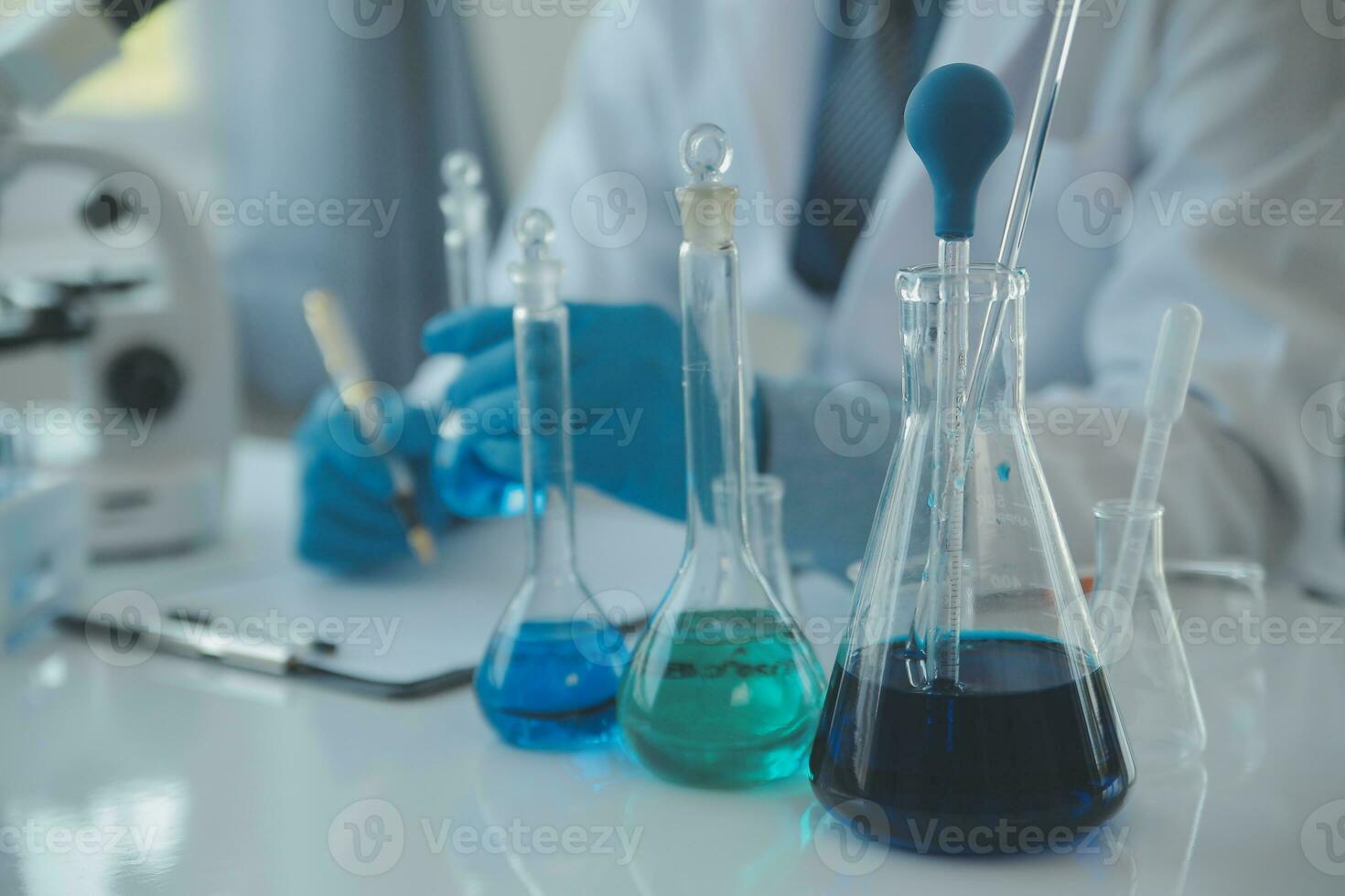 biochemical research scientist team working with microscope for coronavirus vaccine development in pharmaceutical research labolatory, selective focus photo