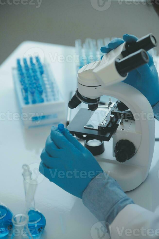 biochemical research scientist team working with microscope for coronavirus vaccine development in pharmaceutical research labolatory, selective focus photo