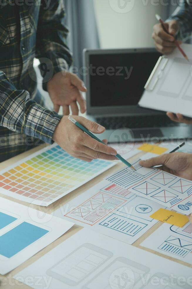 Close up ux developer and ui designer brainstorming about mobile app interface wireframe design on table with customer breif and color code at modern office.Creative digital development agency photo