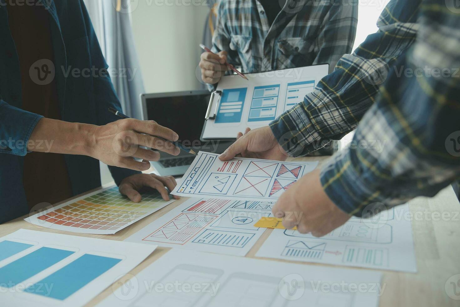 Close up ux developer and ui designer brainstorming about mobile app interface wireframe design on table with customer breif and color code at modern office.Creative digital development agency photo