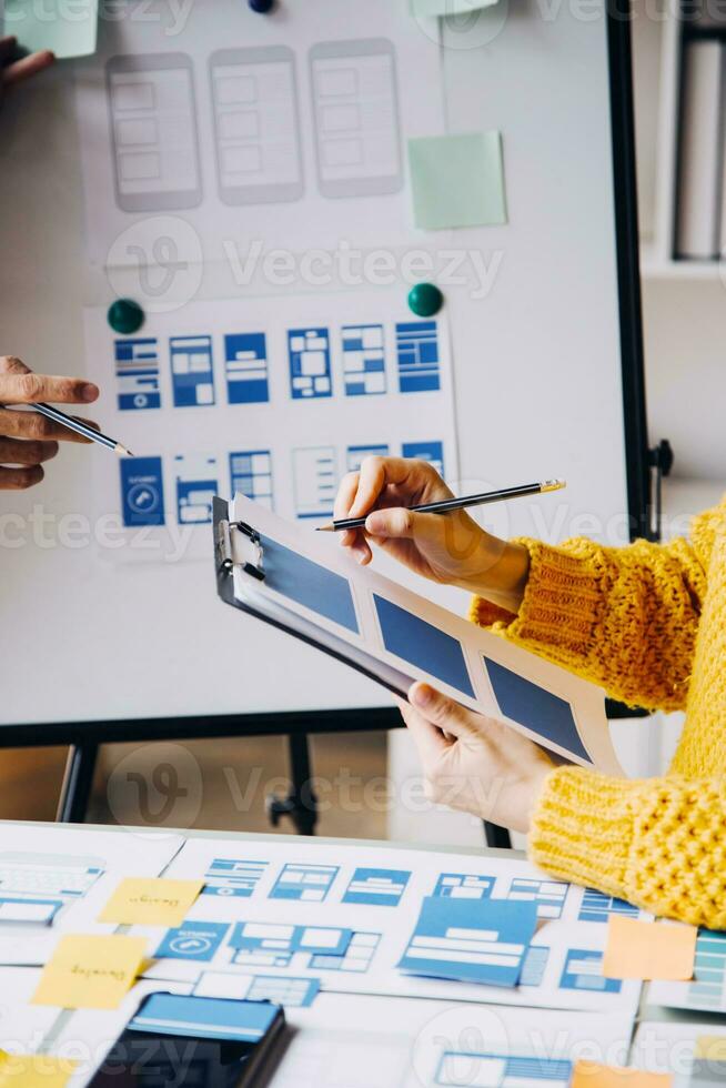 Close up ux developer and ui designer brainstorming about mobile app interface wireframe design on table with customer breif and color code at modern office.Creative digital development agency photo
