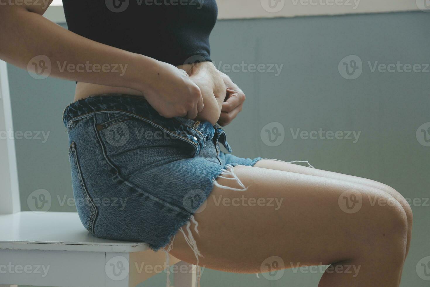 Close up of a belly with scar from c-section and abdominal fat. Women's health. A woman dressed up in sportswear demonstrating her imperfect body after a childbirth with nursery on the background. photo