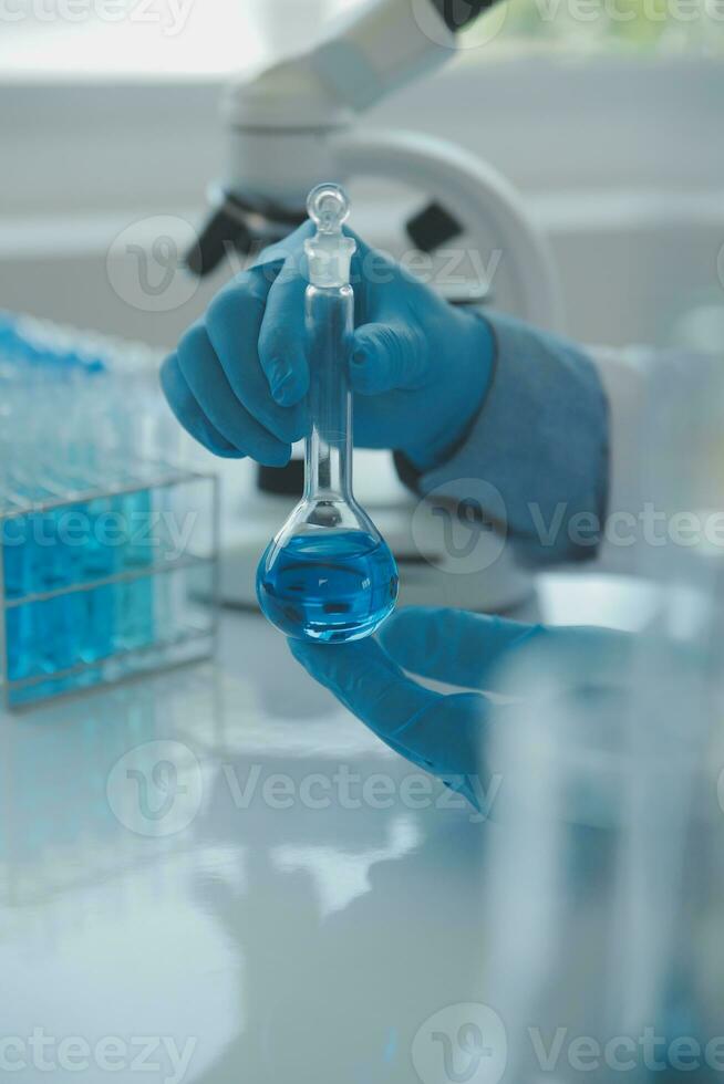 biochemical research scientist team working with microscope for coronavirus vaccine development in pharmaceutical research labolatory, selective focus photo