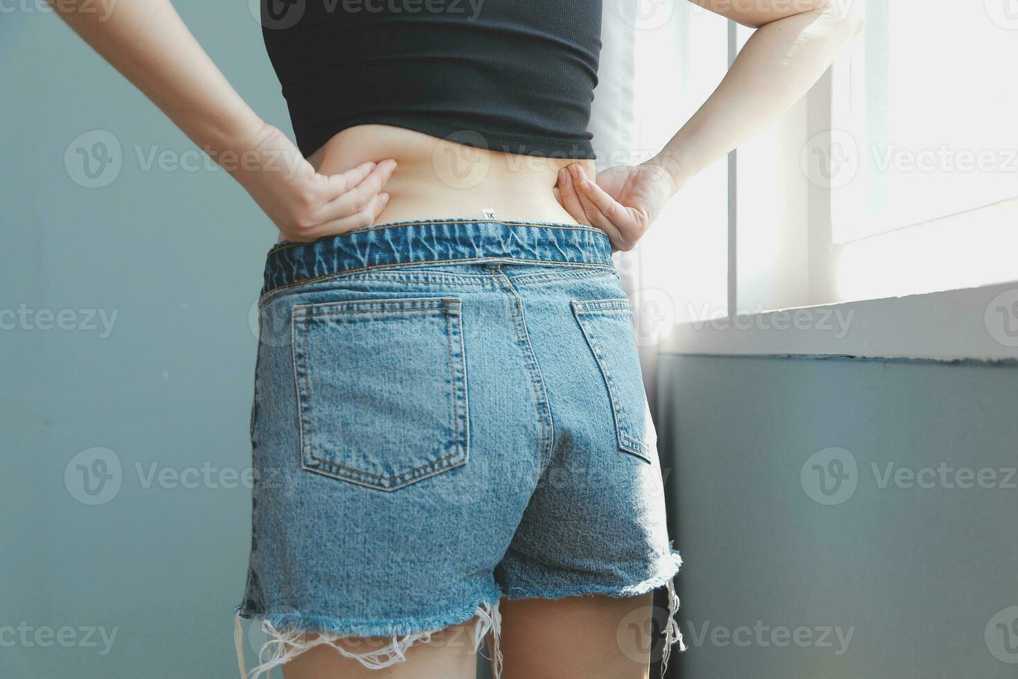 Close up of a belly with scar from c-section and abdominal fat. Women's health. A woman dressed up in sportswear demonstrating her imperfect body after a childbirth with nursery on the background. photo