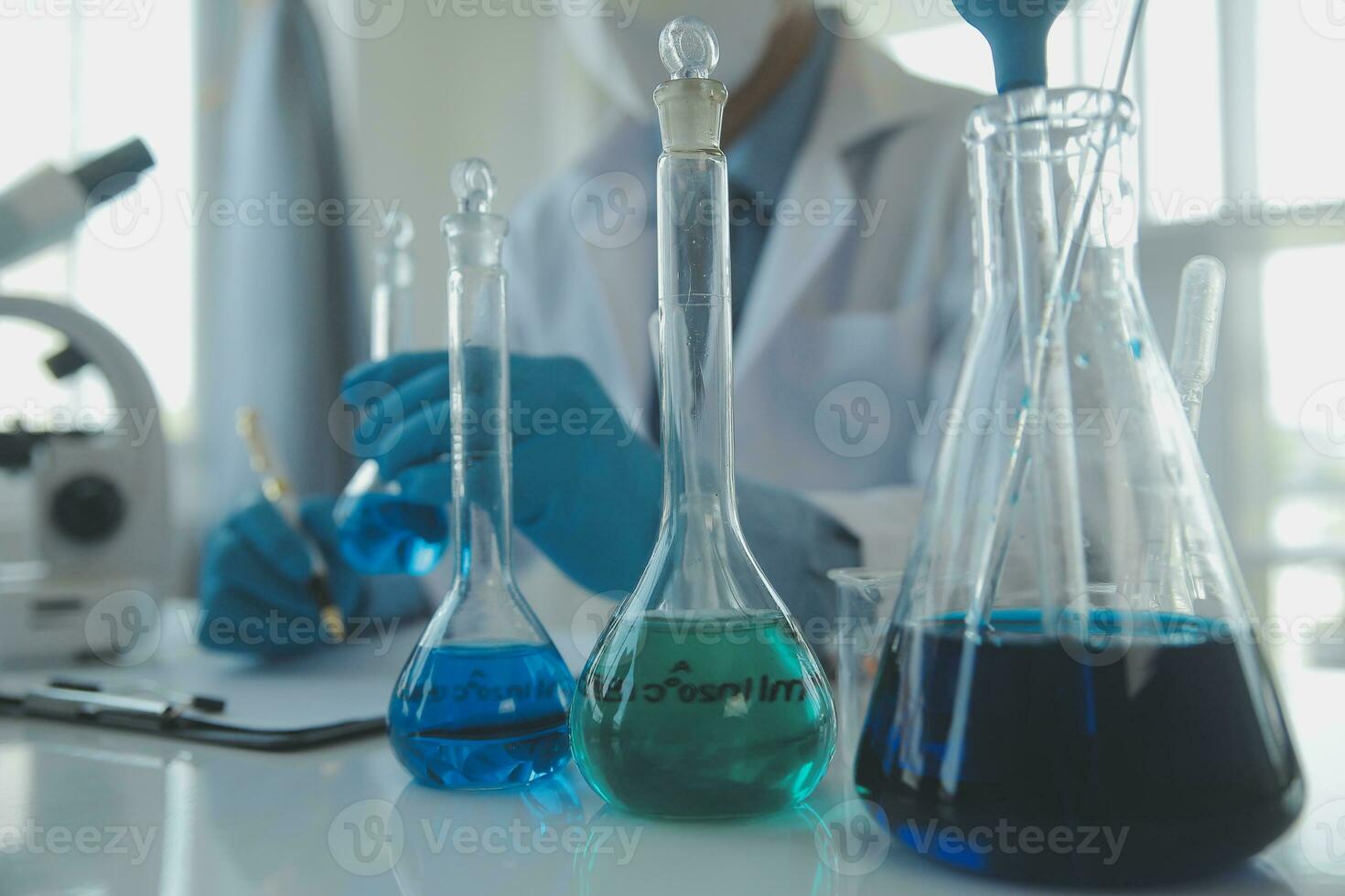 biochemical research scientist team working with microscope for coronavirus vaccine development in pharmaceutical research labolatory, selective focus photo