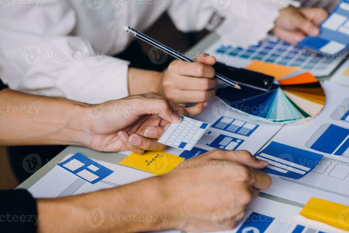 Close up ux developer and ui designer brainstorming about mobile app interface wireframe design on table with customer breif and color code at modern office.Creative digital development agency photo
