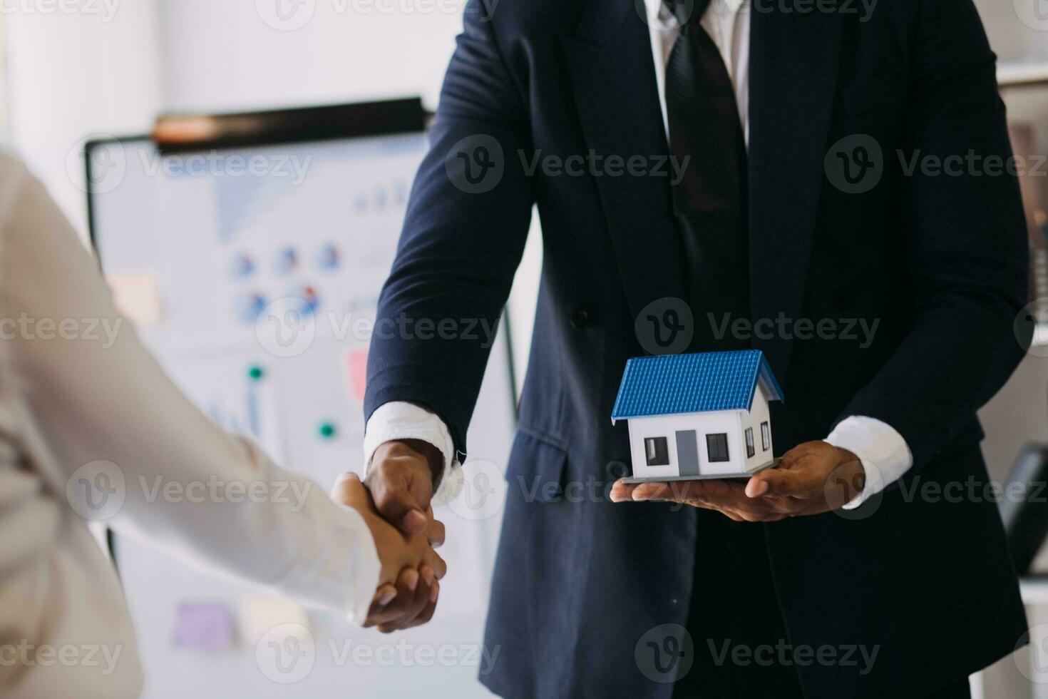 A couple is approaching a housing project to buy, and they are discussing details and advice with a salesperson in a housing project. Real estate trading ideas with couples. photo