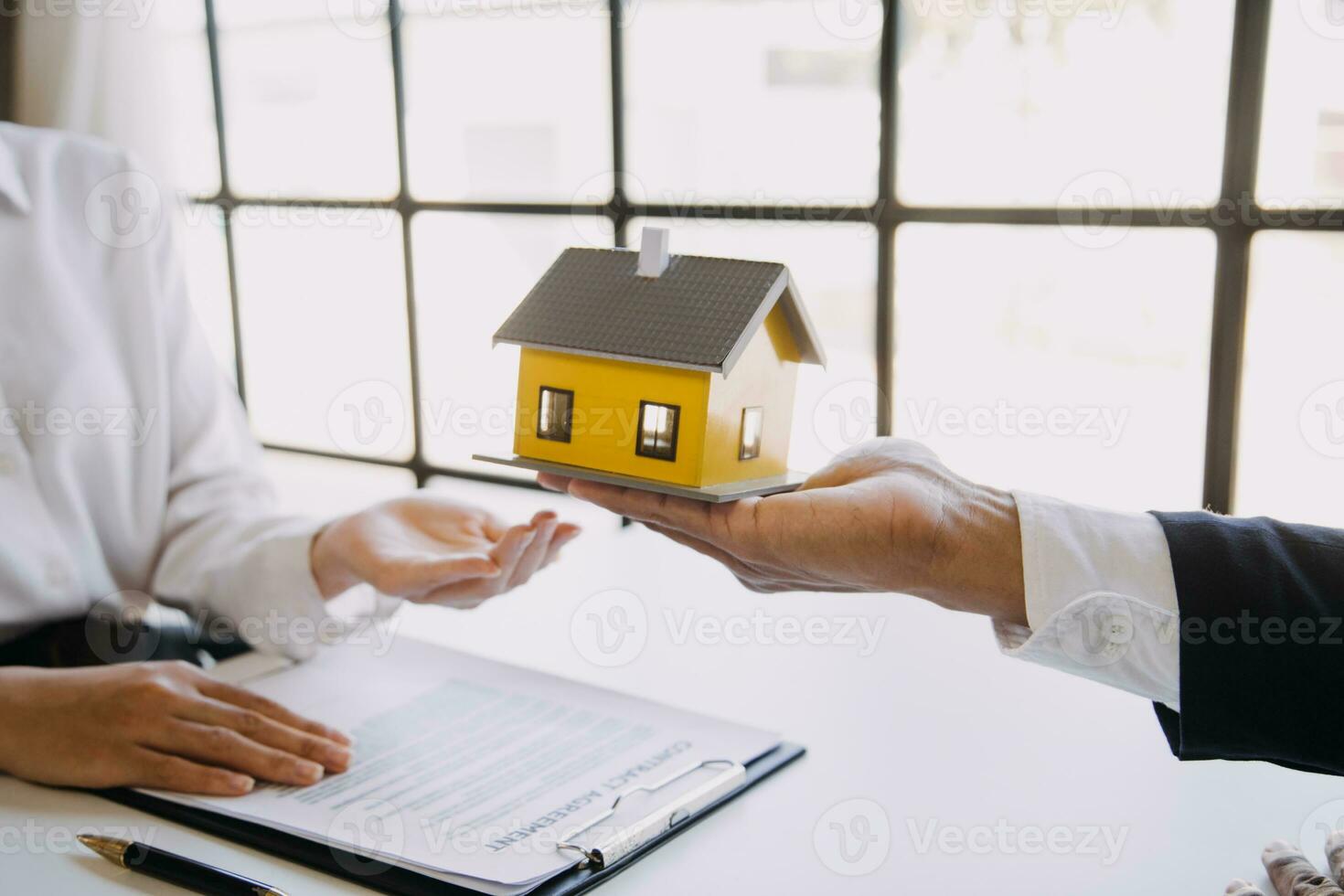A couple is approaching a housing project to buy, and they are discussing details and advice with a salesperson in a housing project. Real estate trading ideas with couples. photo
