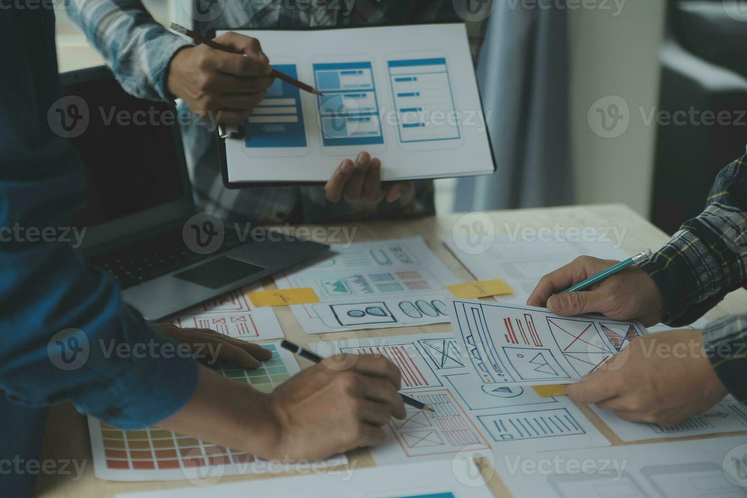 Close up ux developer and ui designer brainstorming about mobile app interface wireframe design on table with customer breif and color code at modern office.Creative digital development agency photo