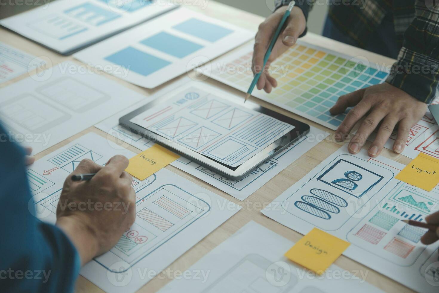 Close up ux developer and ui designer brainstorming about mobile app interface wireframe design on table with customer breif and color code at modern office.Creative digital development agency photo