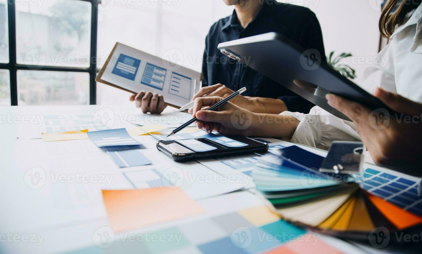 Close up ux developer and ui designer brainstorming about mobile app interface wireframe design on table with customer breif and color code at modern office.Creative digital development agency photo